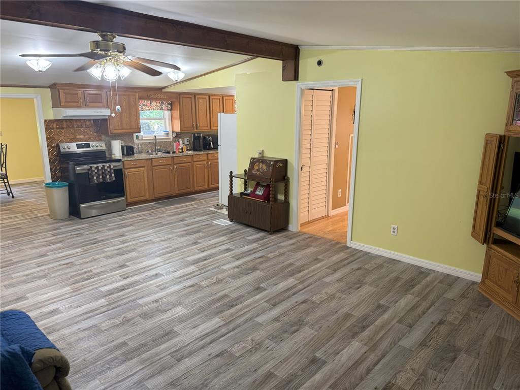 A kitchen with wood cabinets and a living area with light-colored walls and wood-look flooring — 1536 NE 592ND STREET, OLD TOWN, FL