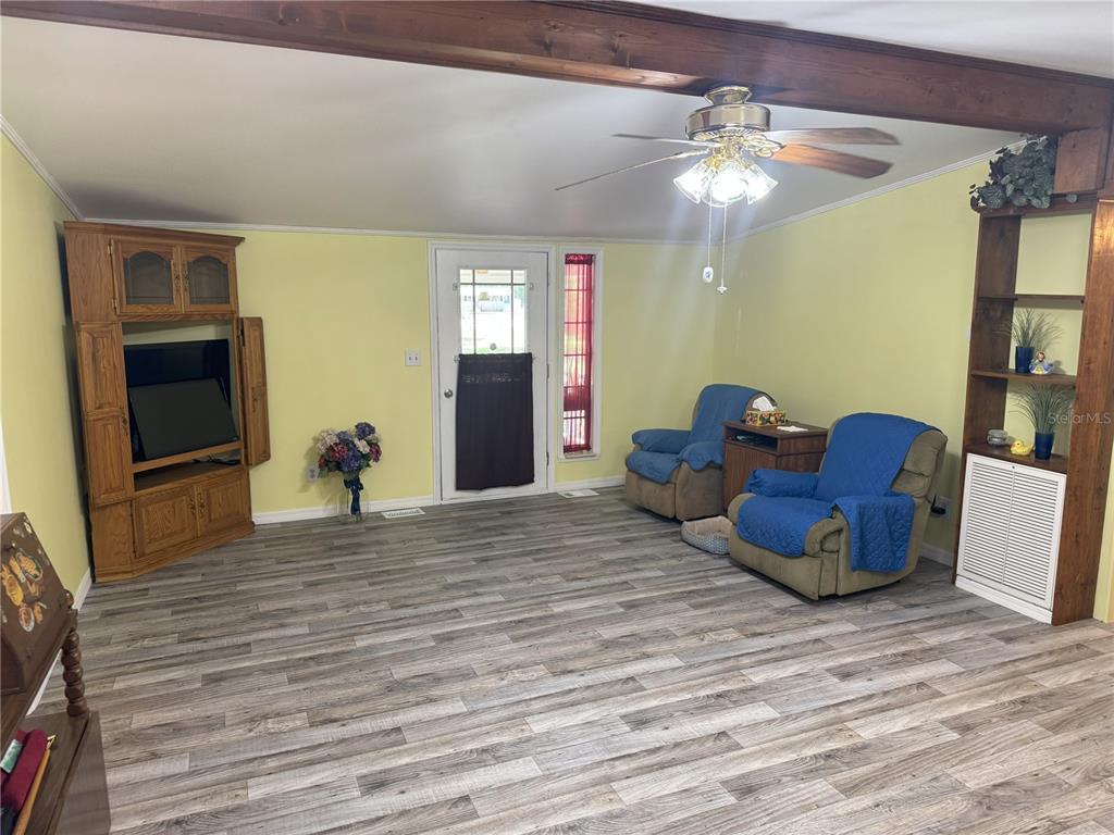 A living room features light yellow walls, wood-look flooring, a ceiling fan, and two recliners — 1536 NE 592ND STREET, OLD TOWN, FL