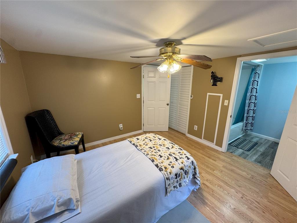 A bedroom features tan walls, wood flooring, a ceiling fan, and an attached bathroom — 1536 NE 592ND STREET, OLD TOWN, FL
