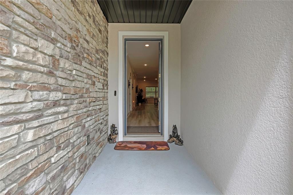 A covered front porch features a stone accent wall, a concrete floor, and an open doorway — 32 CARNATION COURT, HOMOSASSA, FL