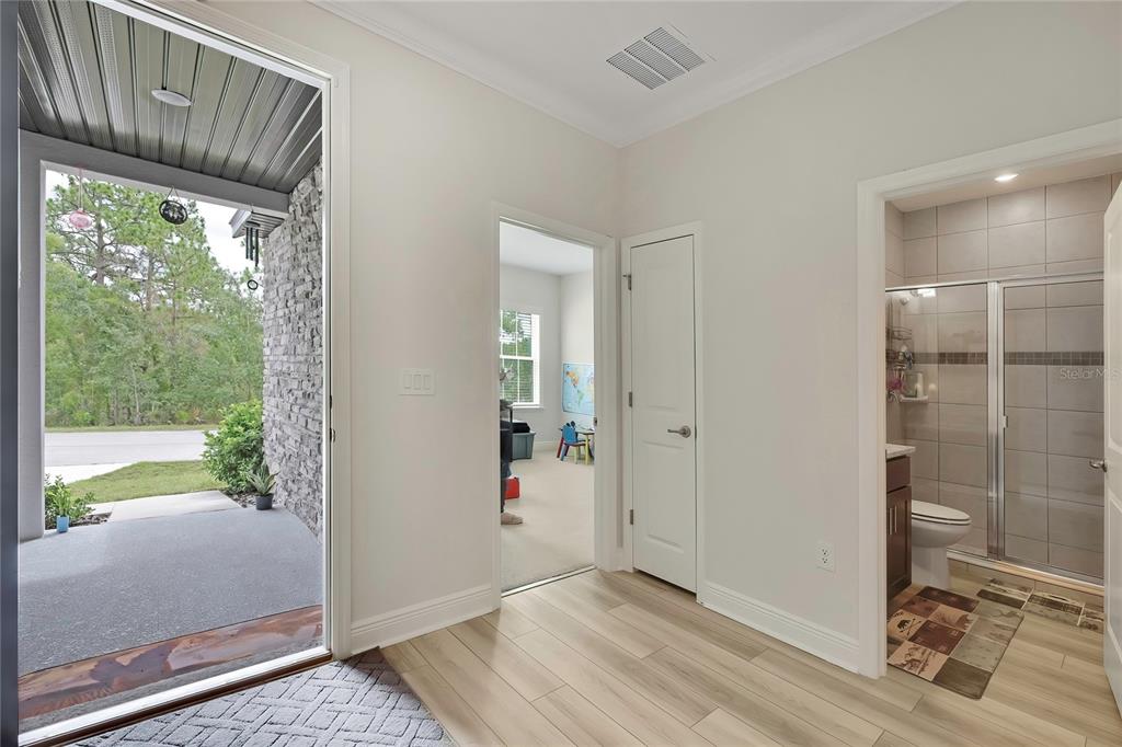 An entryway with light wood-look flooring leads to a bedroom, a closet, and a bathroom — 32 CARNATION COURT, HOMOSASSA, FL