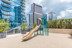 An outdoor playground with a slide on a rooftop terrace surrounded by city skyscrapers — 801 S Miami Ave # 4308, Miami FL 33130, MIAMI, FL