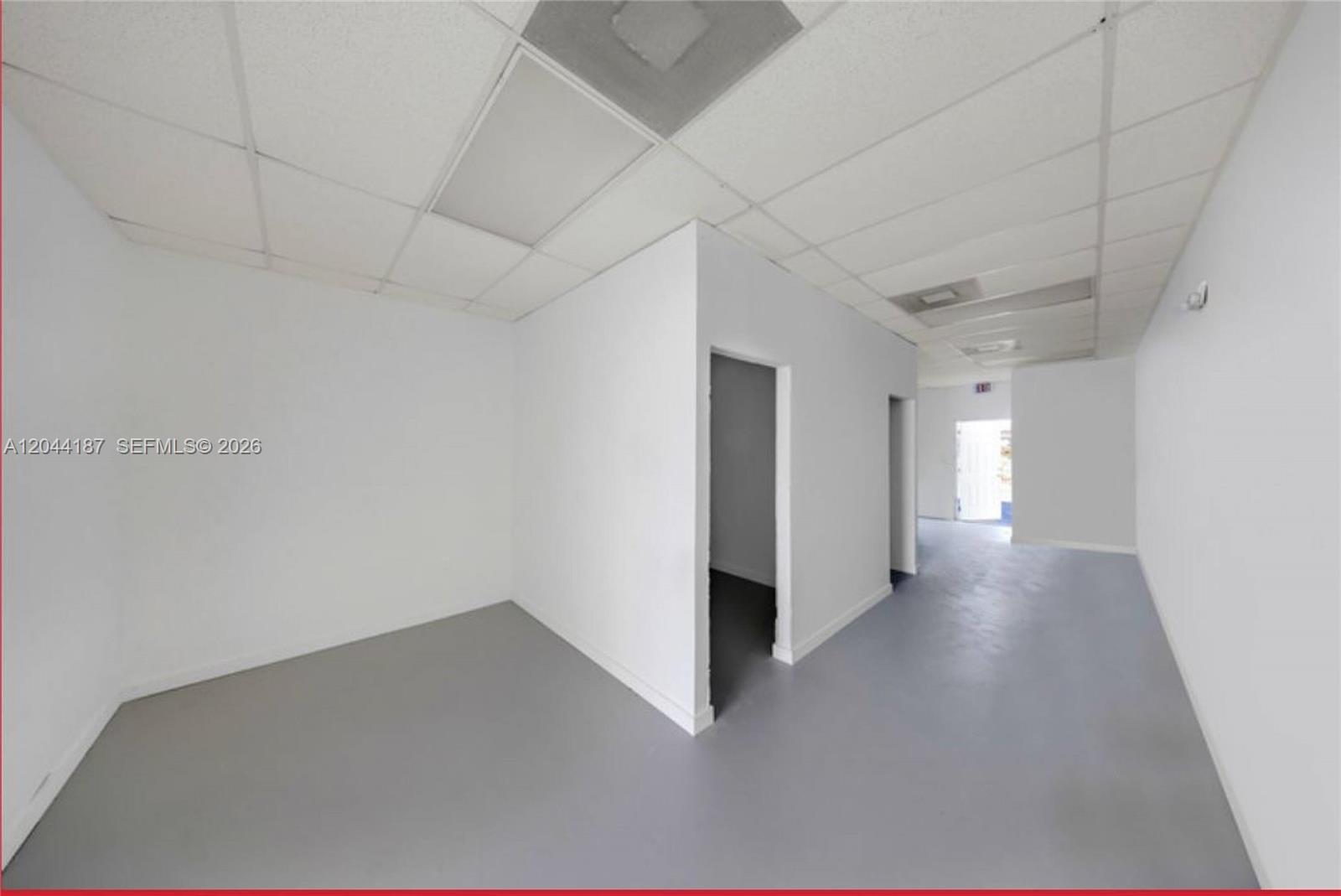 An interior view of a vacant commercial space with white walls, grey flooring, and drop ceilings — 3241 NW 7th St # 3251, Miami FL 33125, MIAMI, FL
