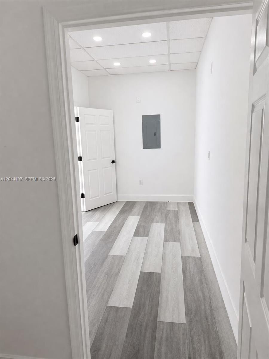 A small room features gray wood-look flooring, white walls, a drop ceiling, and an electrical panel — 3241 NW 7th St # 3251, Miami FL 33125, MIAMI, FL
