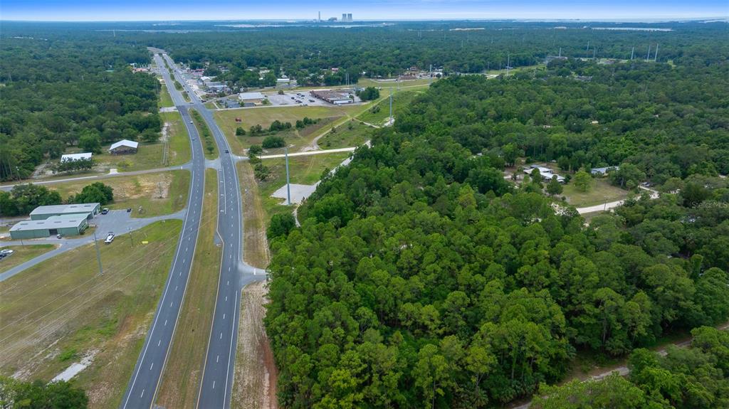 An aerial view shows a multi-lane highway running alongside a large, wooded plot of land — RACHEL AVE & HWY 19 N, INGLIS, FL
