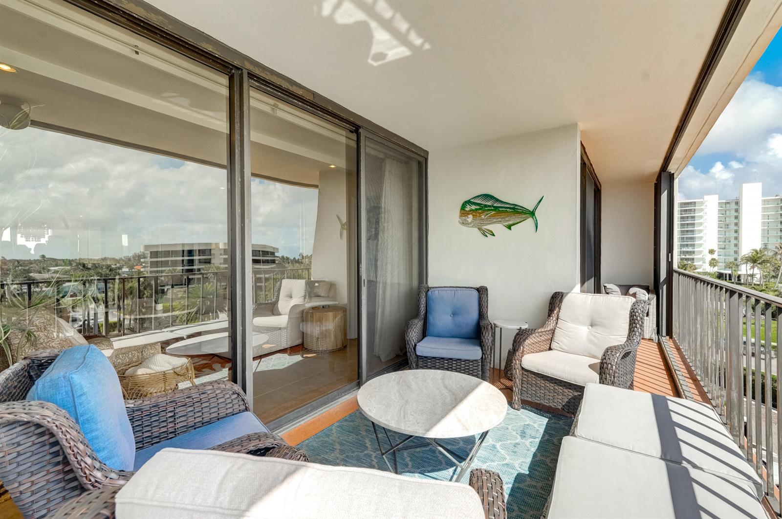 A balcony with wicker furniture, a round stone table, and a metal fish wall decoration — 225 Beach Road # 503, Tequesta FL 33469, TEQUESTA, FL