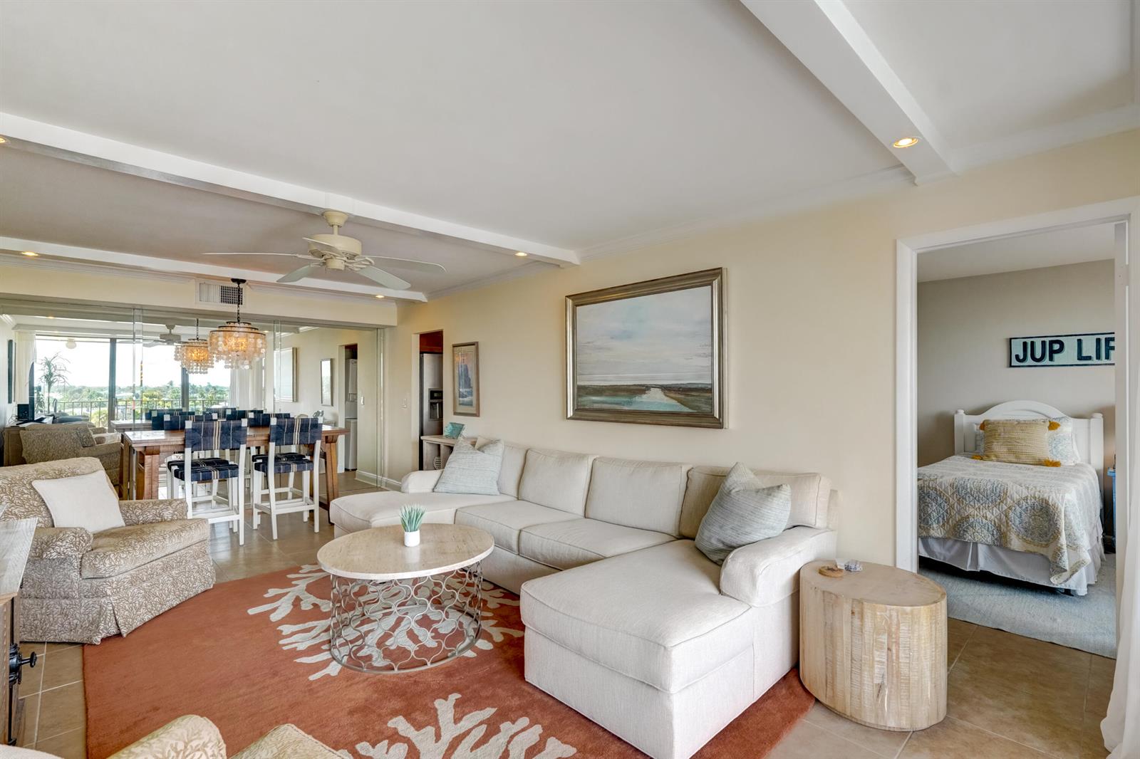 A living room with a white sectional sofa, coral area rug, and adjacent dining area — 225 Beach Road # 503, Tequesta FL 33469, TEQUESTA, FL