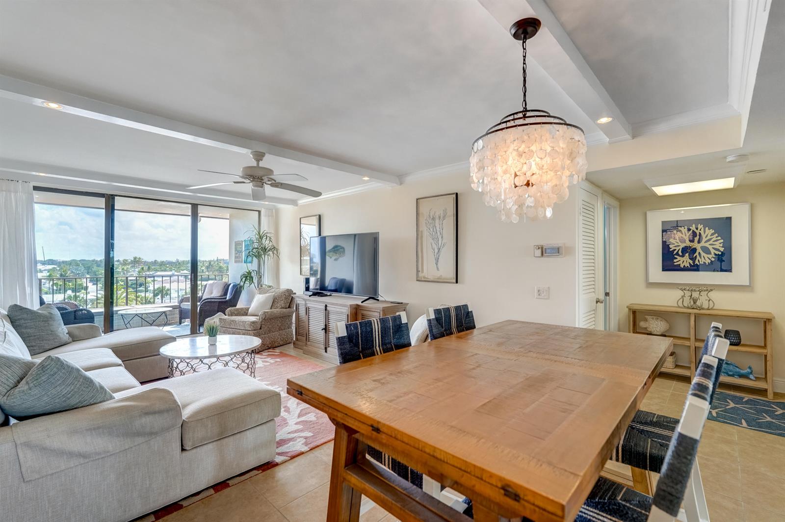 A bright living and dining area features a wooden table, sectional sofa, and balcony view — 225 Beach Road # 503, Tequesta FL 33469, TEQUESTA, FL