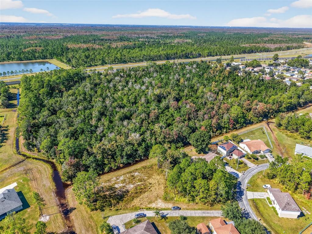 An aerial view shows a large, wooded vacant lot adjacent to a residential neighborhood — 955 CAMBRIDGE COURT, KISSIMMEE, FL