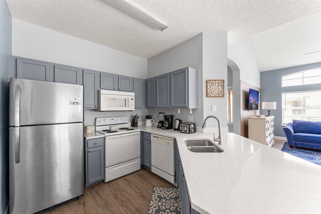 A kitchen with gray cabinets, stainless steel appliances, and a white quartz countertop island — 2739 SUN KEY PLACE, KISSIMMEE, FL