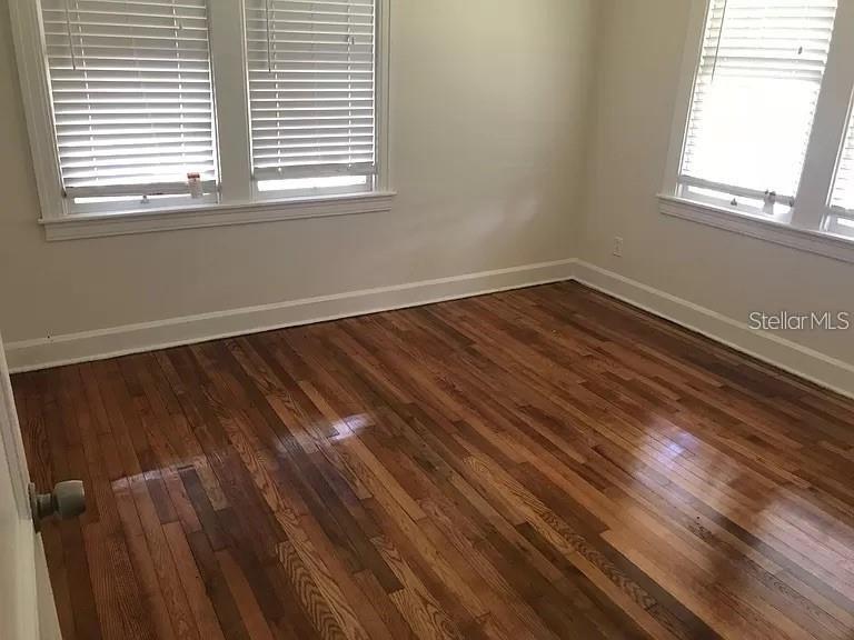 An empty room features hardwood floors, white walls, and two windows with closed blinds — 545 15TH AVENUE S, ST PETERSBURG, FL
