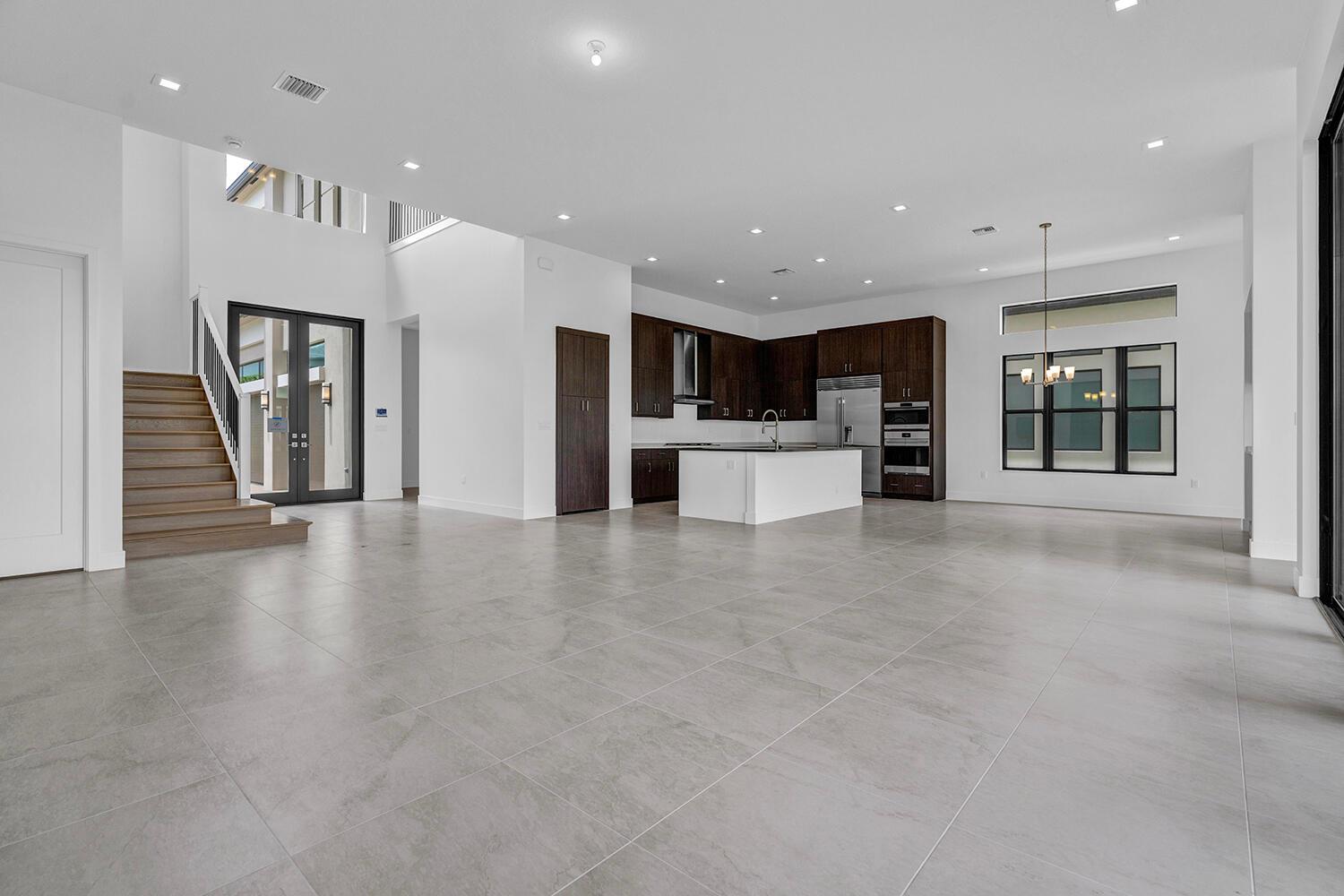 An open-concept kitchen and living area features large grey floor tiles and dark wood cabinetry — 9523 Riverside Park Drive, Boca Raton FL 33434, BOCA RATON, FL