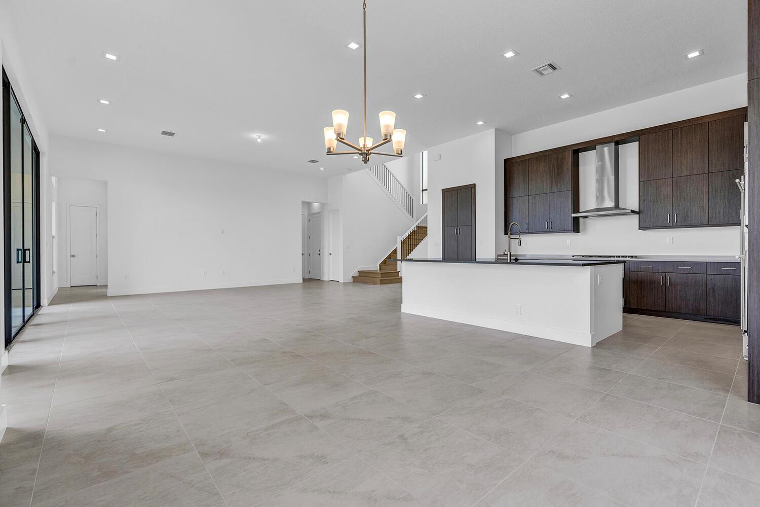 A modern open-concept kitchen and living area with dark wood cabinets and light tile floors — 9523 Riverside Park Drive, Boca Raton FL 33434, BOCA RATON, FL