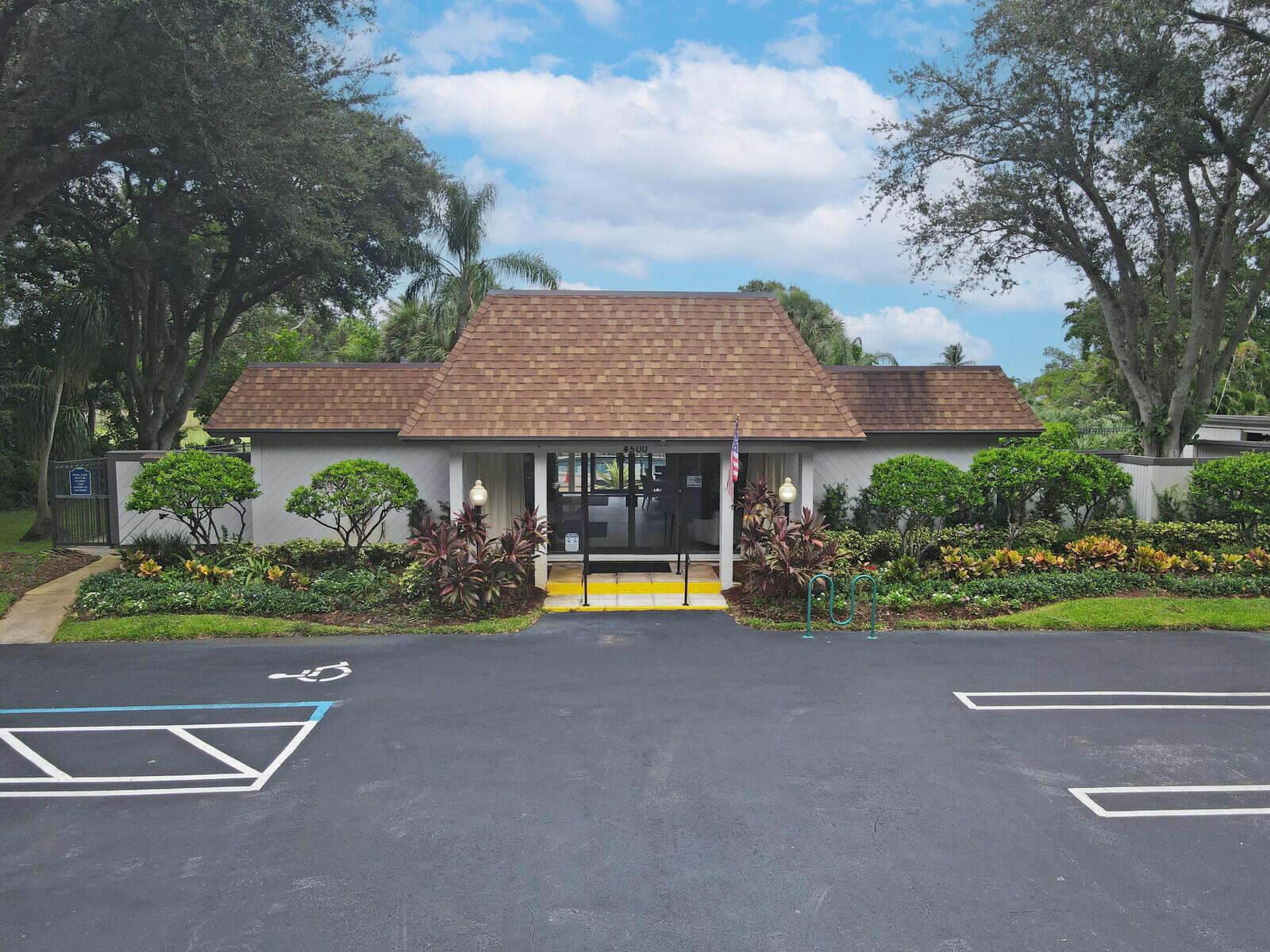 A single-story building with a brown shingled roof and a central glass entrance door — 3680 ARELIA Drive S, Delray Beach FL 33445, DELRAY BEACH, FL