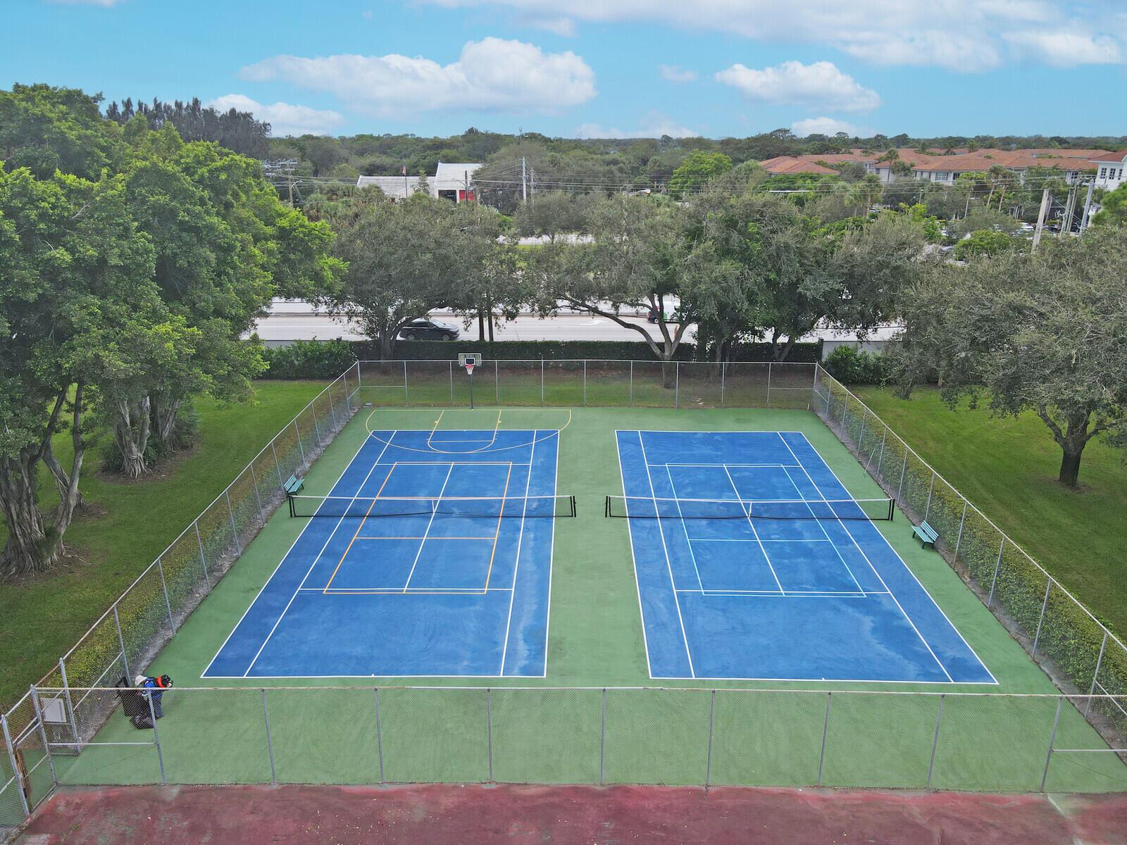 An aerial view of two blue tennis courts enclosed by a chain-link fence — 3680 ARELIA Drive S, Delray Beach FL 33445, DELRAY BEACH, FL