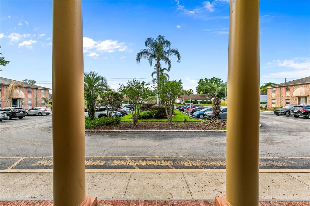 A view of a parking lot and apartment buildings framed by two large columns — 416 BANYON TREE CIRCLE UNIT 206, MAITLAND, FL
