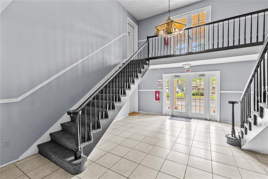 A tiled entryway features a staircase with dark carpet and a second-floor balcony railing — 416 BANYON TREE CIRCLE UNIT 206, MAITLAND, FL