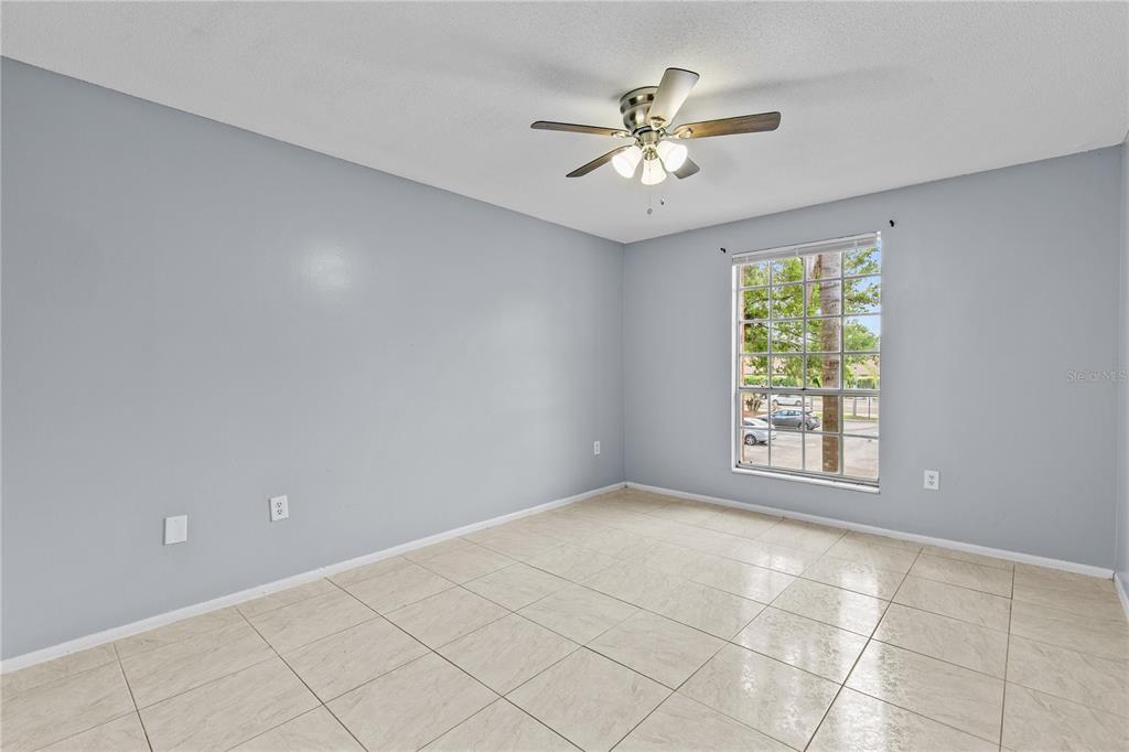 An empty bedroom features light blue walls, beige tile flooring, and a ceiling fan — 416 BANYON TREE CIRCLE UNIT 206, MAITLAND, FL