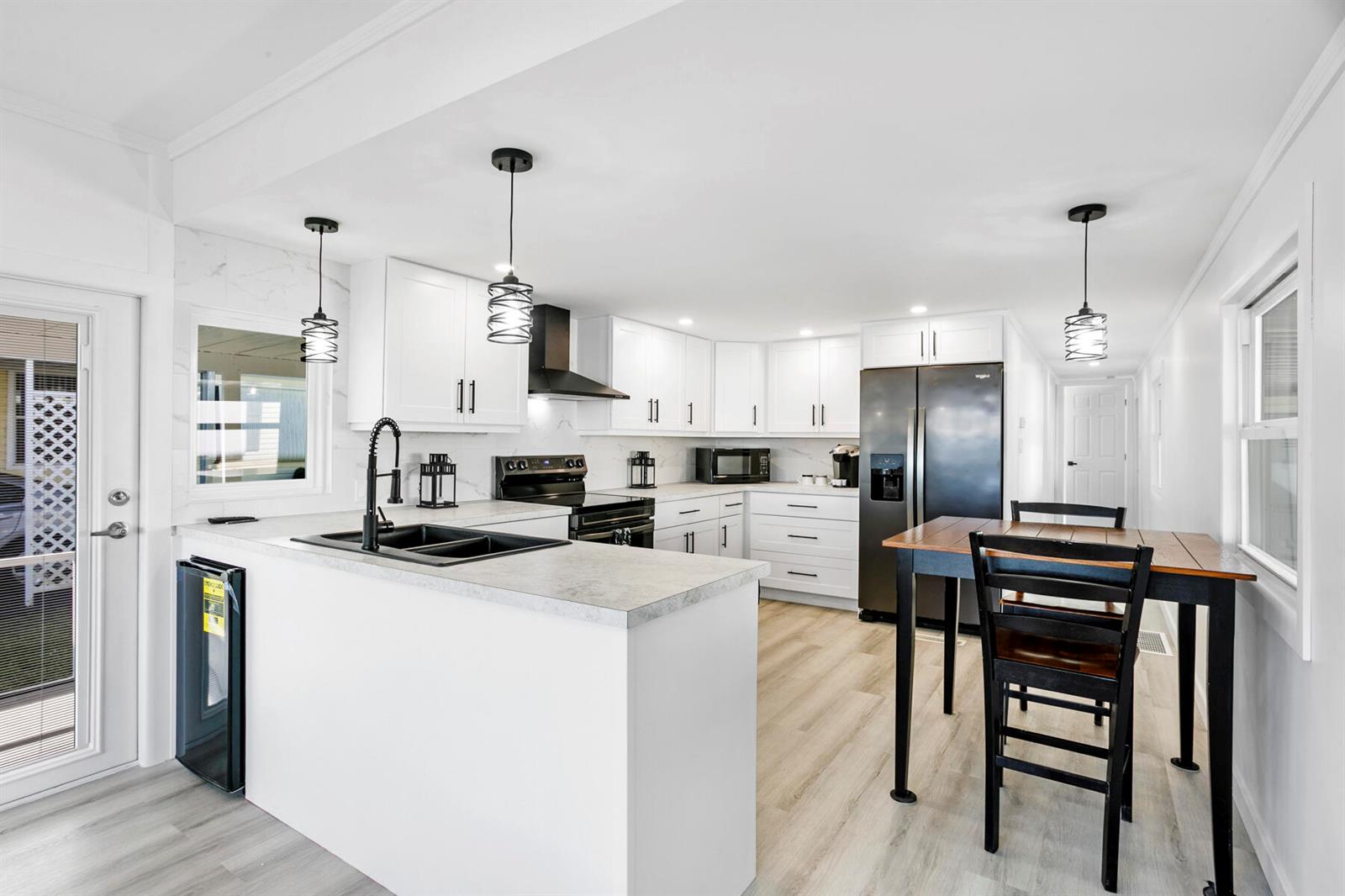 A modern kitchen features white cabinets, black appliances, a peninsula with a sink, and dining area — 3003 Bimini Bay, Boynton Beach FL 33436, BOYNTON BEACH, FL