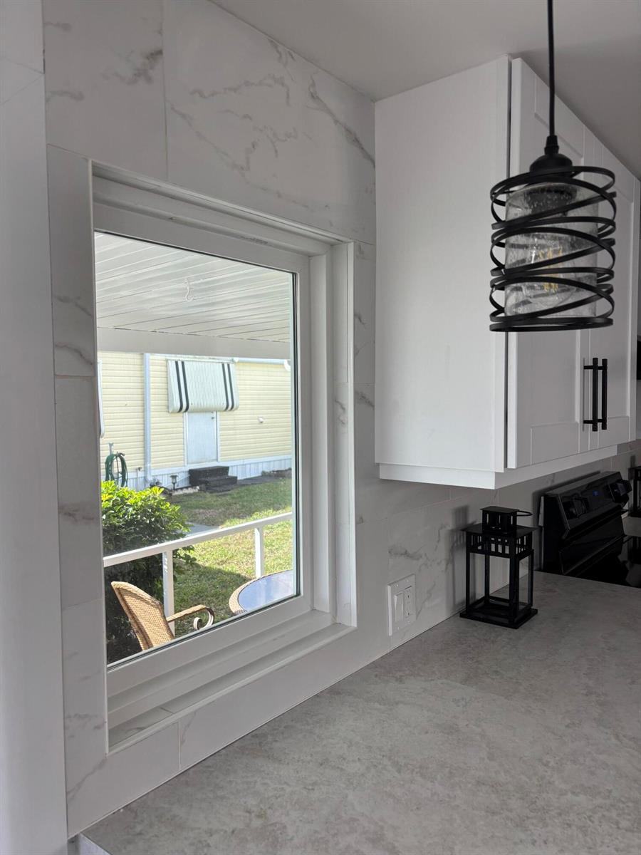 A kitchen window with marble-look tile trim overlooks a yard with a yellow house — 3003 Bimini Bay, Boynton Beach FL 33436, BOYNTON BEACH, FL