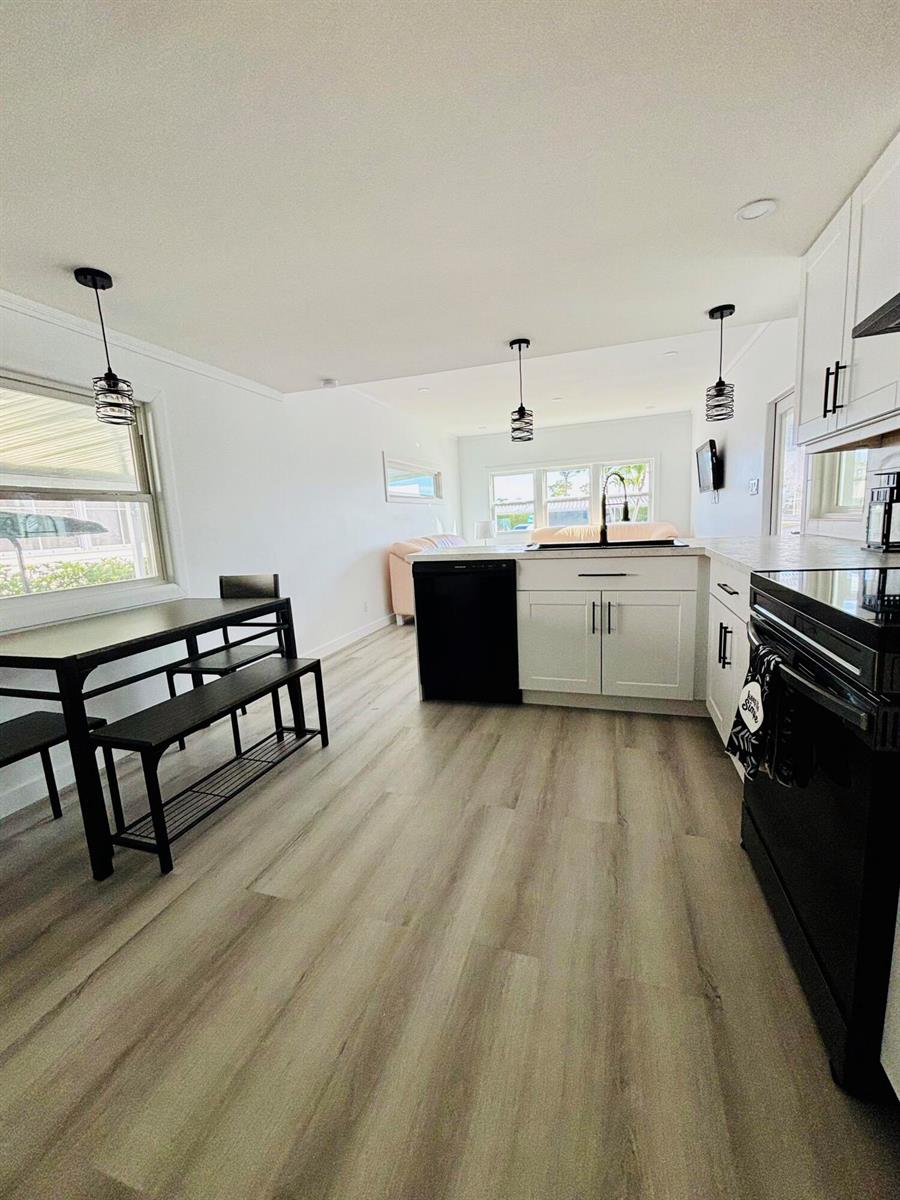 A kitchen with white cabinets, black appliances, and a dining area with a bench table — 3003 Bimini Bay, Boynton Beach FL 33436, BOYNTON BEACH, FL