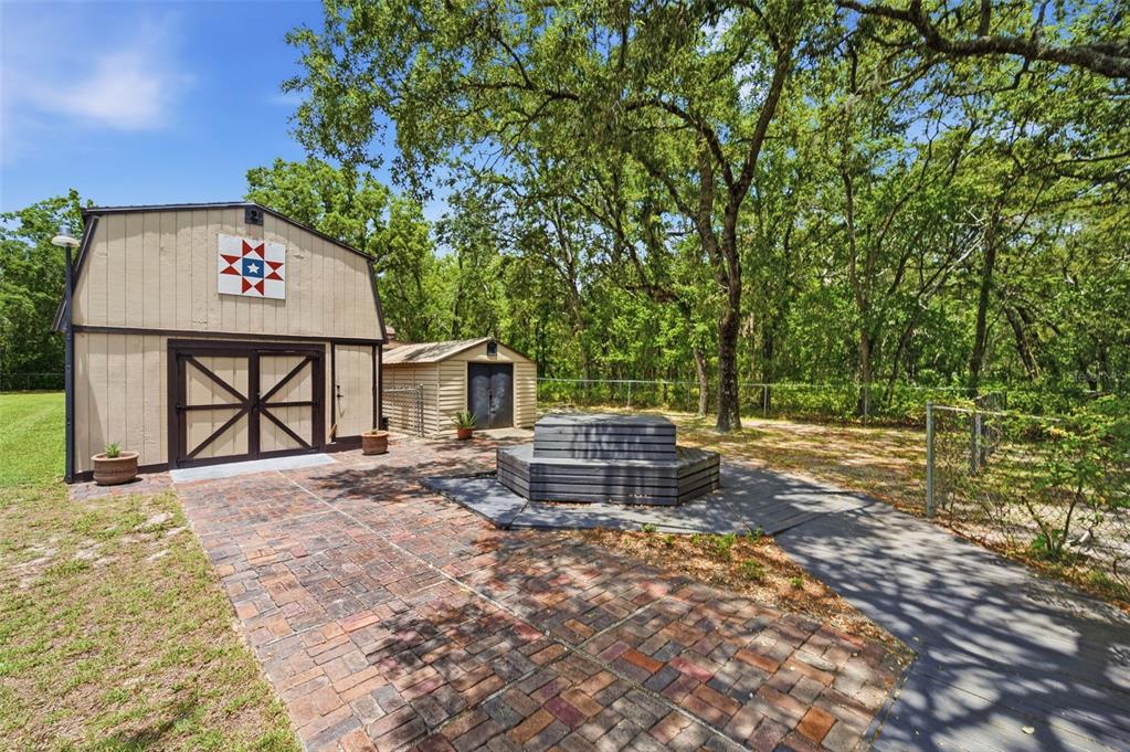 A tan barn with a quilt square, a brick walkway, and a wooden deck in a yard — 15041 CAMROSE AVENUE, SPRING HILL, FL