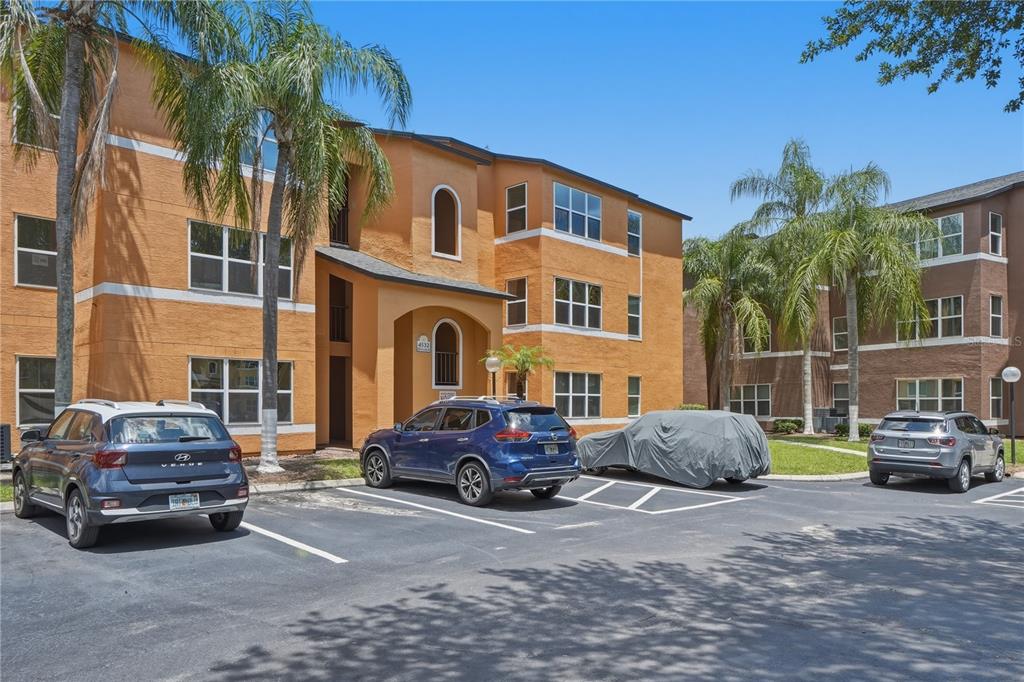 A three-story orange apartment building with a parking lot and palm trees in front — 4532 COMMANDER DRIVE UNIT 2121, ORLANDO, FL