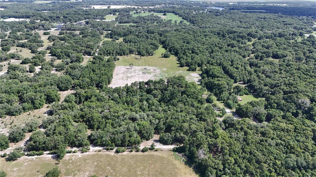 An aerial view shows a large, partially cleared plot of land surrounded by dense forest — 5501 CEMETERY & SADLER ROADS, MOUNT DORA, FL