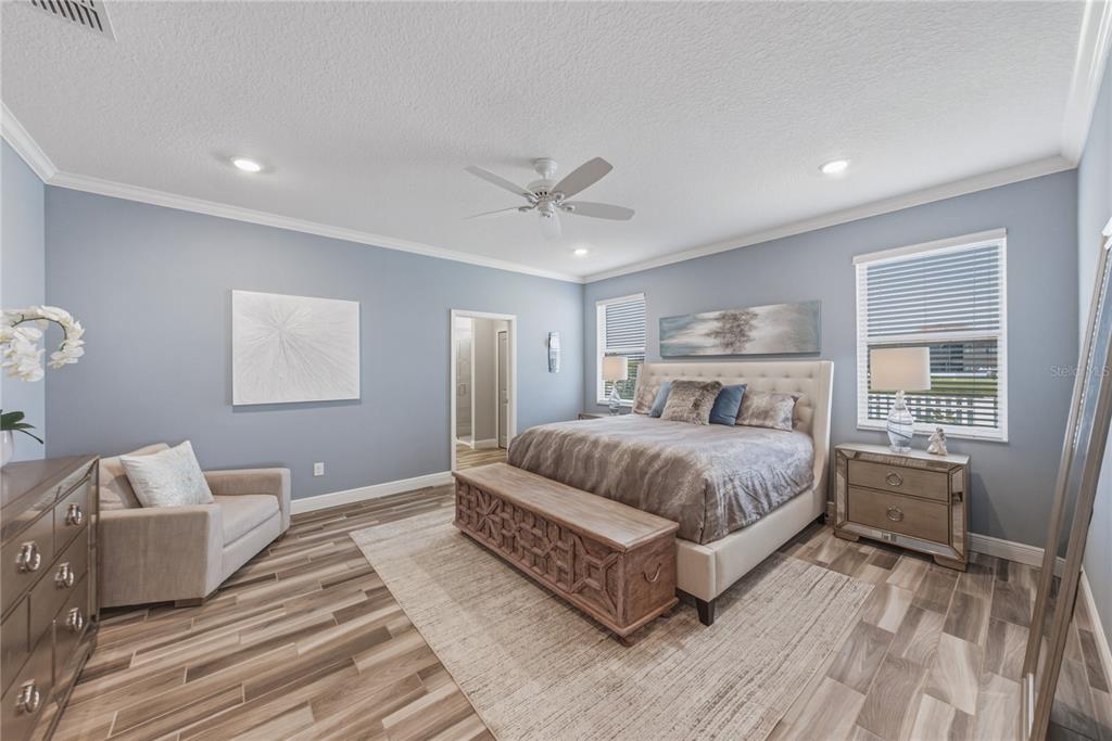 A bedroom with light blue walls, wood-look tile flooring, a bed, and a sitting chair — 11947 SAND MYRTLE ROAD, RIVERVIEW, FL