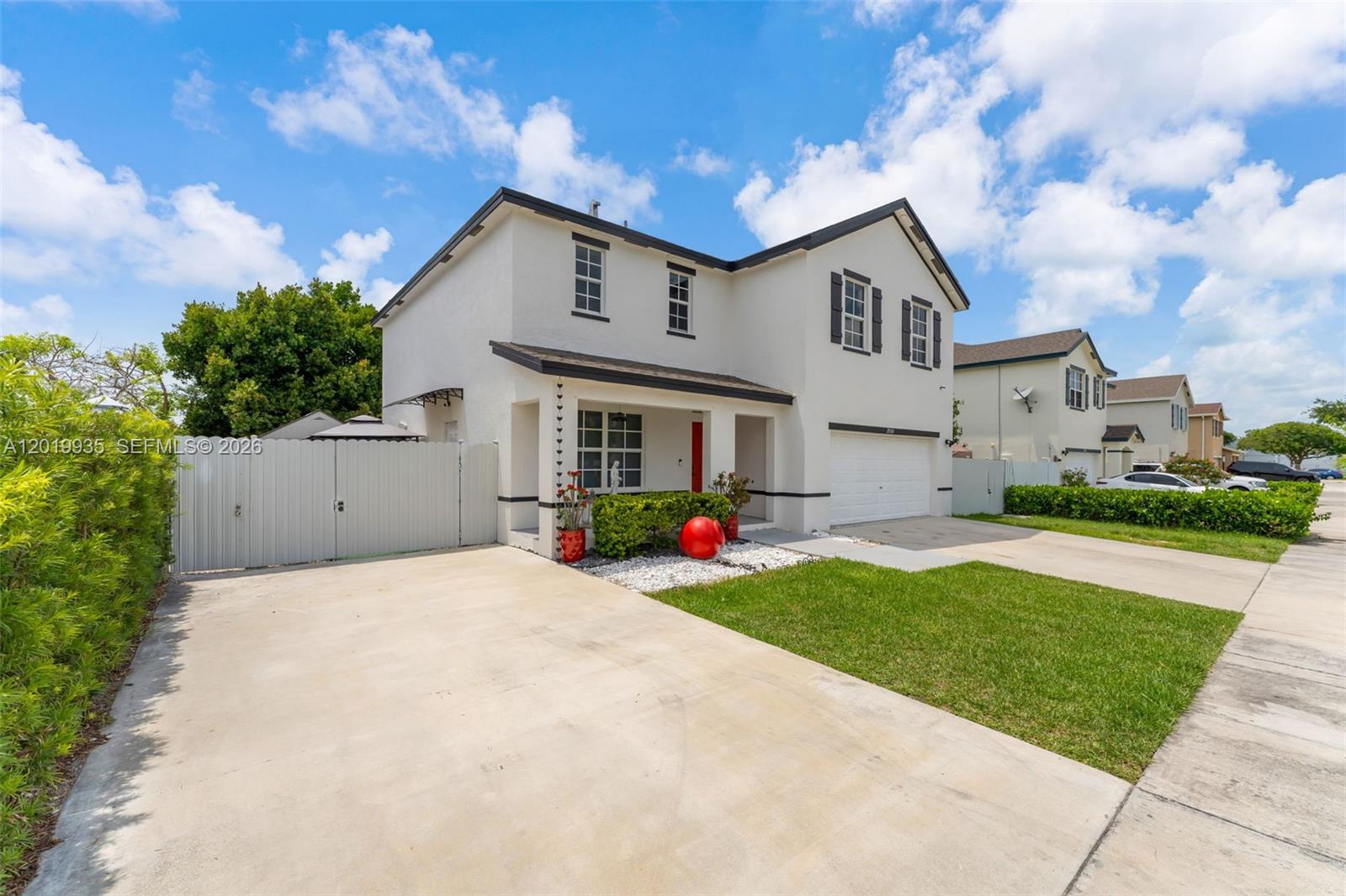 A two-story white house with a garage, driveway, and a fenced side yard — HOMESTEAD, FL