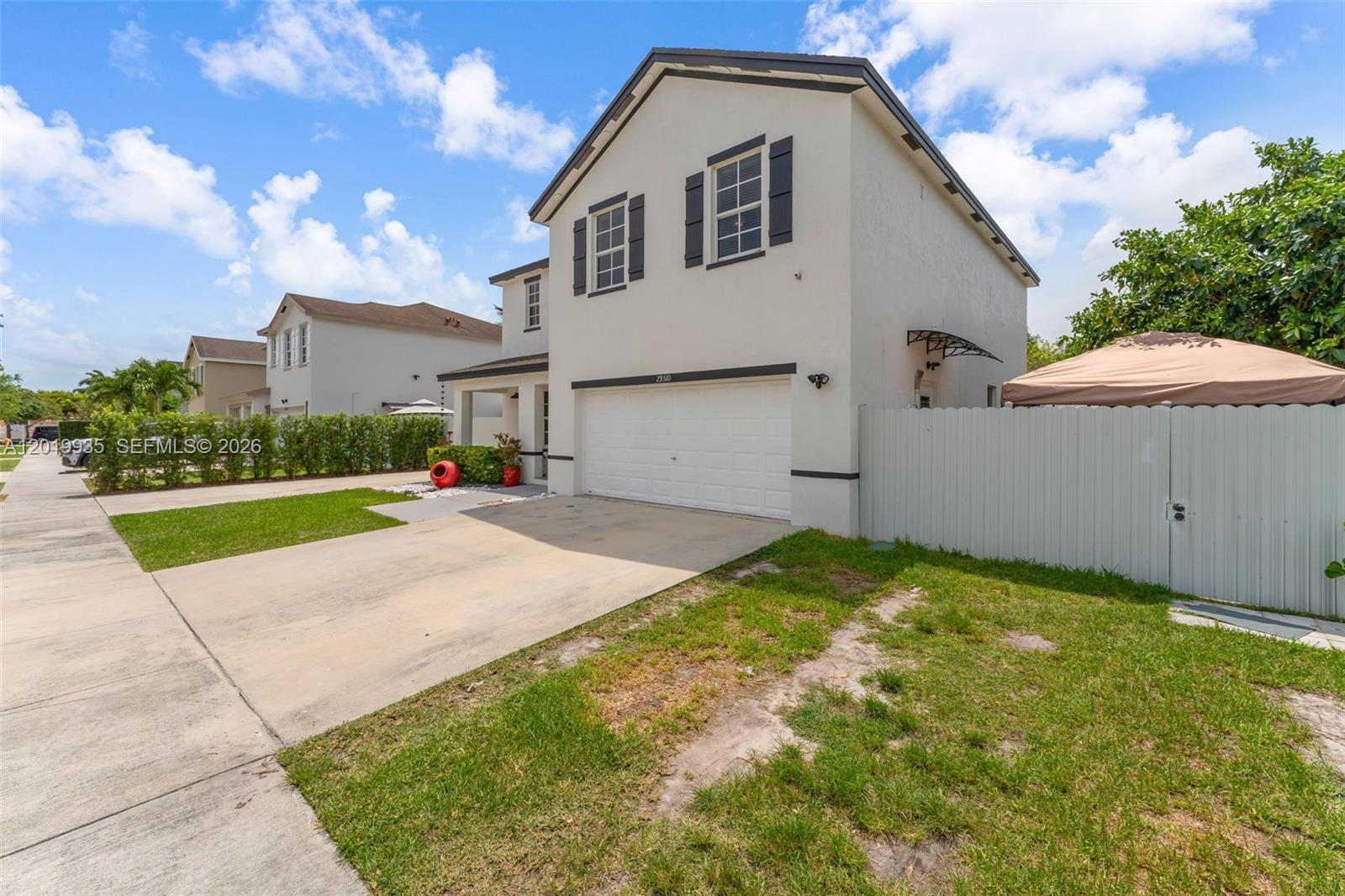 A two-story house with a white stucco exterior, a garage, and a fenced side yard — HOMESTEAD, FL
