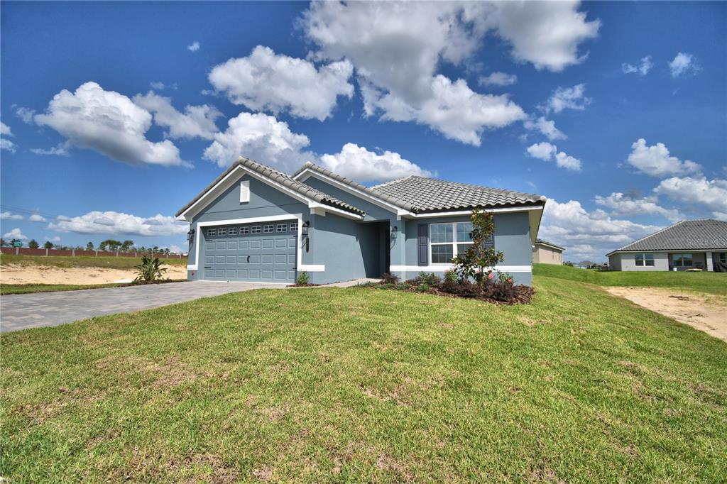 A single-story blue house with a two-car garage and a paved driveway — 5427 WATERSIDE DRIVE, AUBURNDALE, FL