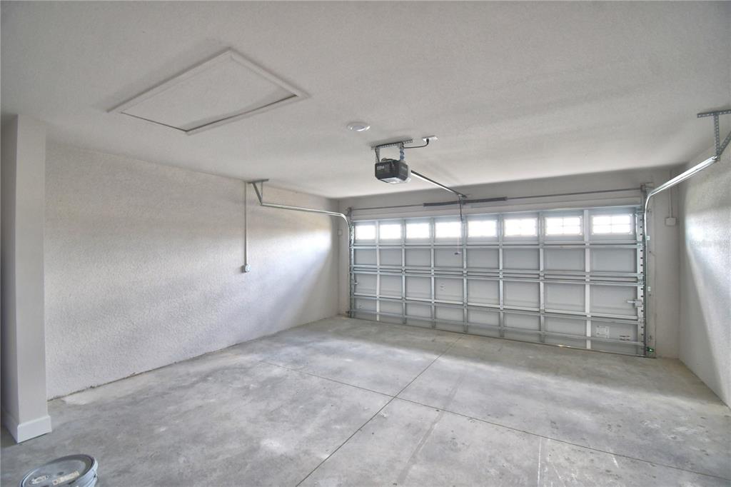 An empty garage features a concrete floor, textured walls, and a sectional overhead door — 5427 WATERSIDE DRIVE, AUBURNDALE, FL