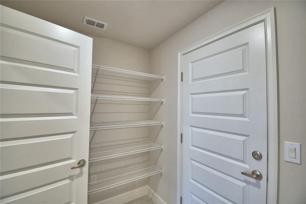 A pantry with white wire shelving sits between two white paneled doors — 5427 WATERSIDE DRIVE, AUBURNDALE, FL