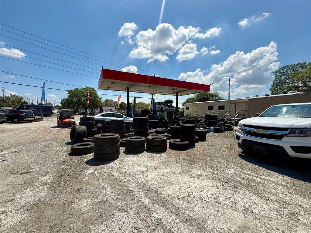 An outdoor auto repair lot features a service canopy, stacks of tires, and parked vehicles — 2658 OVERLAND ROAD, APOPKA, FL