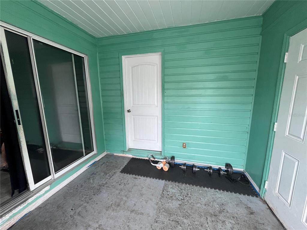 A covered patio features teal horizontal siding, a sliding glass door, and a white door — 33 W JOHNSON AVENUE, LAKE WALES, FL