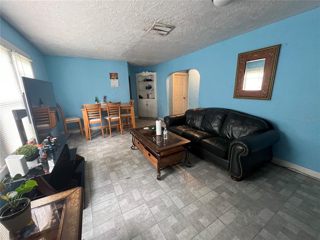 A living room with blue walls, tile flooring, a black leather sofa, and dining area — 33 W JOHNSON AVENUE, LAKE WALES, FL