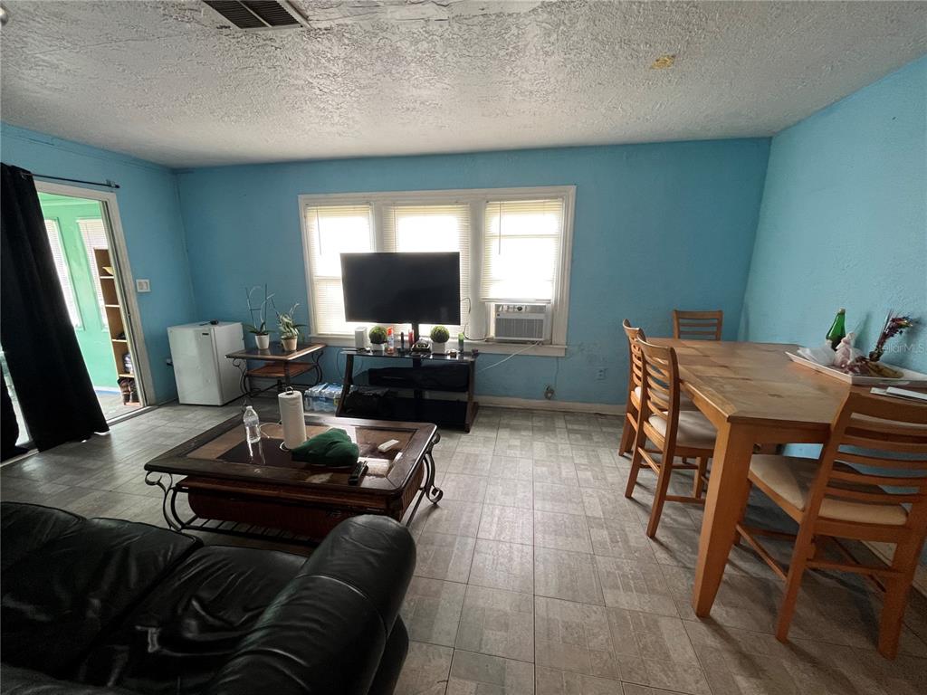 A living and dining area with light blue walls, tile flooring, and a television stand — 33 W JOHNSON AVENUE, LAKE WALES, FL