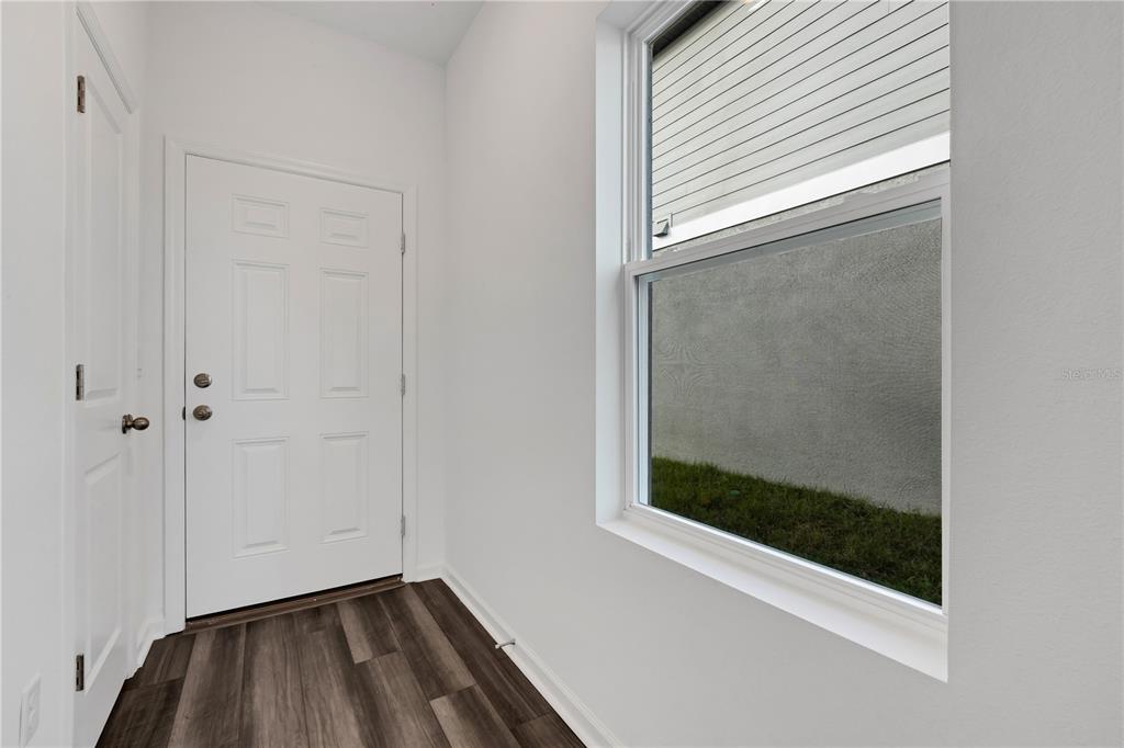 An entryway features white walls, dark wood-look flooring, a white door, and a large window — 35605 BUTTONWEED TRAIL, ZEPHYRHILLS, FL