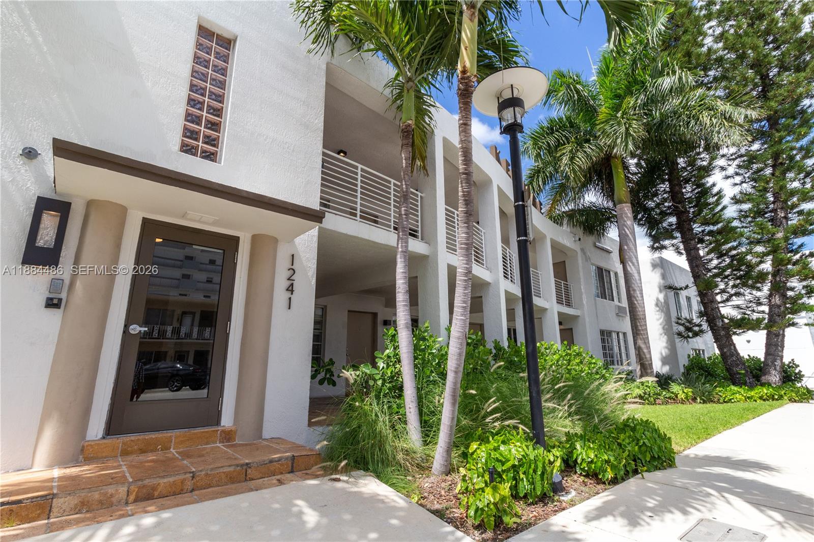 A white multi-story apartment building stands behind a parking lot with palm trees — 1241 14th St # 9, Miami Beach FL 33139, MIAMI BEACH, FL