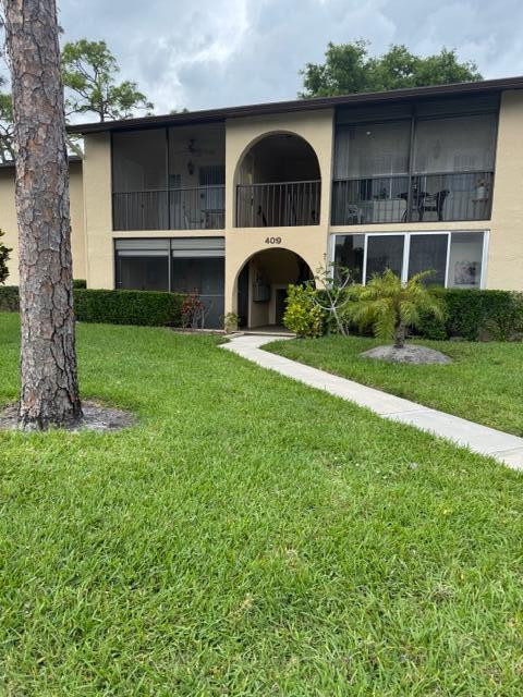 A two-story apartment building features screened balconies, arched entryways, and a concrete walkway — 409 Pine Glen Lane # 1, FL 33463, FL