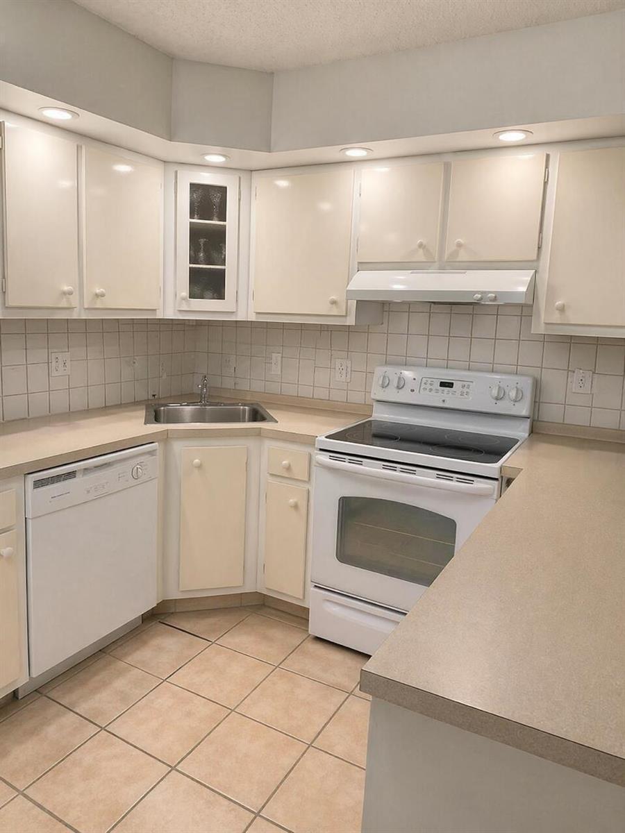 A kitchen with white cabinets, a white stove, a dishwasher, and beige tiled flooring — 409 Pine Glen Lane # 1, FL 33463, FL