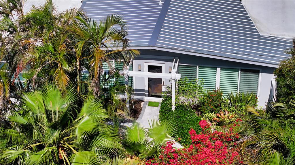 An exterior view of a house entrance surrounded by lush tropical landscaping and palm trees — 425 MCKINLEY DRIVE, SARASOTA, FL
