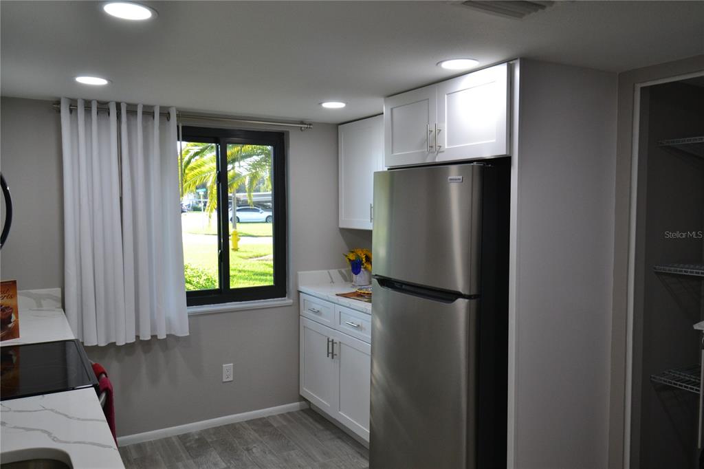 A kitchen features white cabinets, stainless steel appliances, quartz countertops, and a window with curtains — 135 W CYPRESS COURT, OLDSMAR, FL
