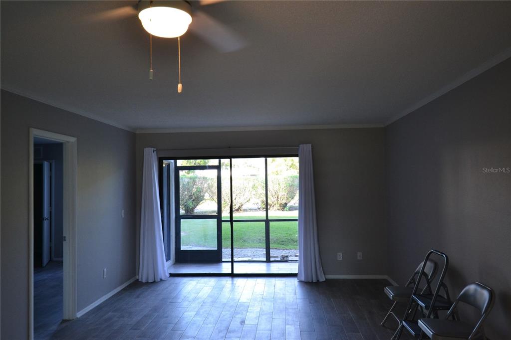 A living room with gray walls, wood-look flooring, a ceiling fan, and a screened patio — 135 W CYPRESS COURT, OLDSMAR, FL