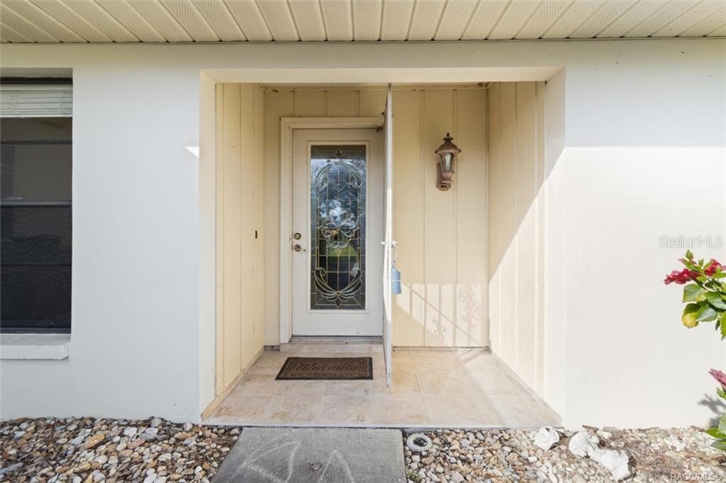A front entryway features a white door with a decorative glass insert and tile flooring — 11684 W SUNNYBROOK COURT, CRYSTAL RIVER, FL