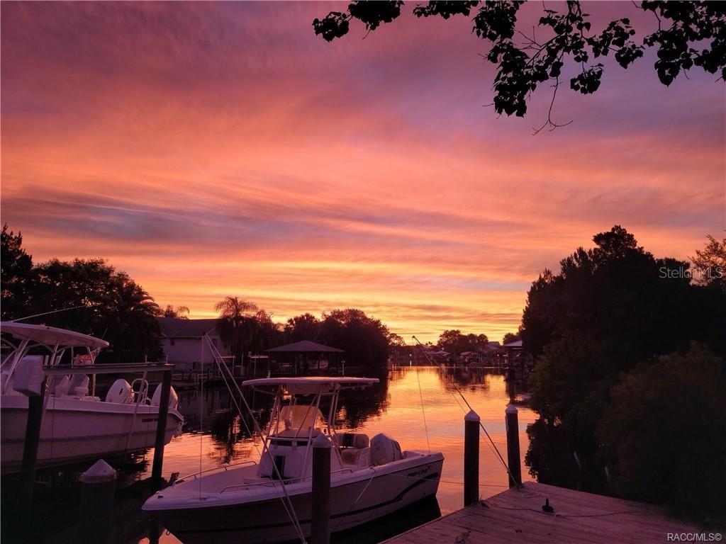A sunset view over a canal with two boats docked at a wooden pier — 11684 W SUNNYBROOK COURT, CRYSTAL RIVER, FL