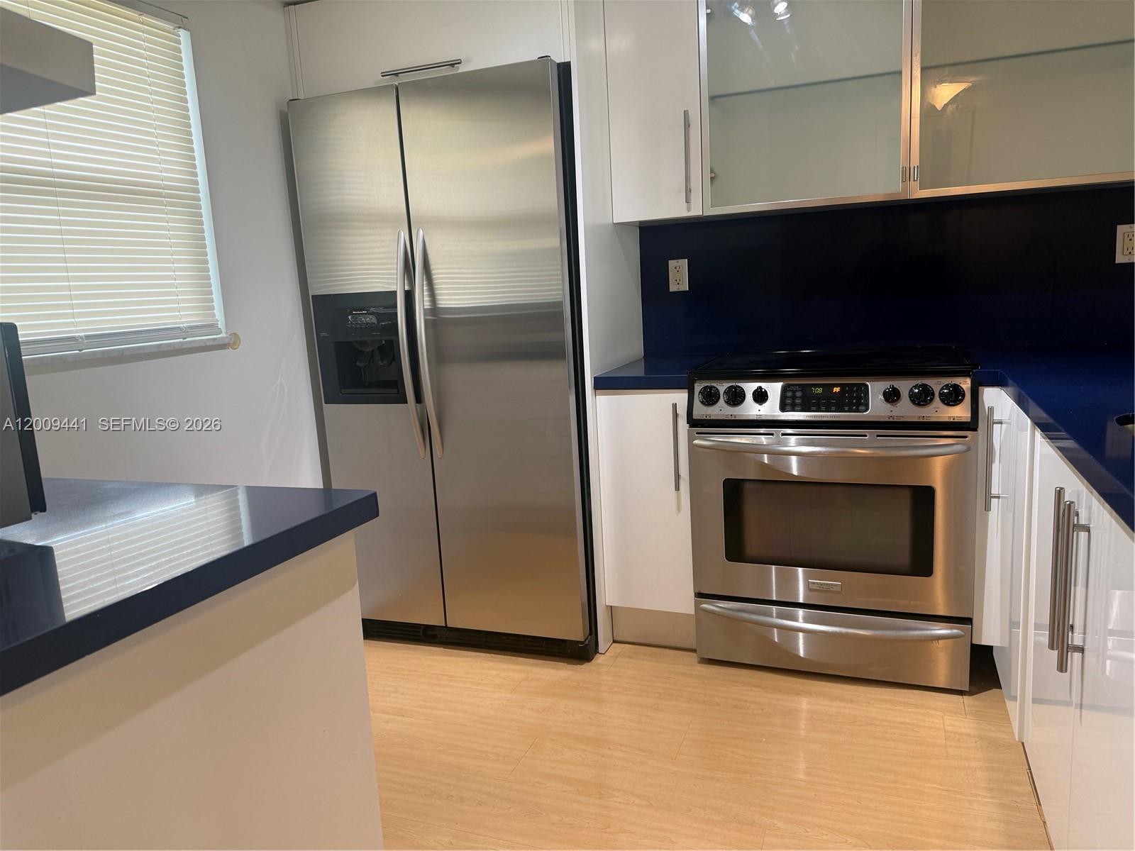A kitchen features white cabinets, stainless steel appliances, and a dark blue countertop — 100 Edgewater Dr # 236, Coral Gables FL 33133, CORAL GABLES, FL