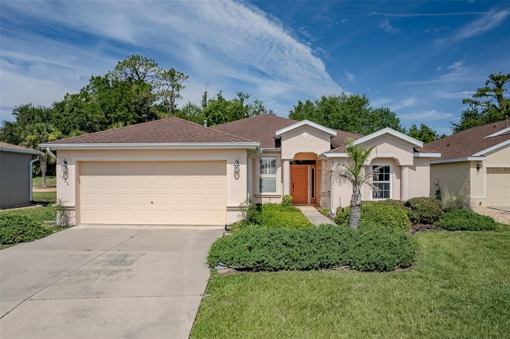 A single-story suburban house with a beige stucco exterior, a two-car garage, and landscaping — 1520 SW 152ND PLACE, OCALA, FL
