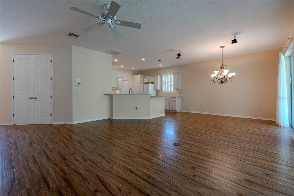 An open-concept living and dining area features wood-look flooring, a ceiling fan, and a kitchen — 1520 SW 152ND PLACE, OCALA, FL